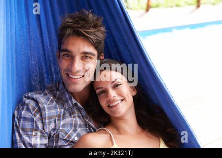 Happy holiday together. Portrait of an affectionate young couple lying in a hammock. Stock Photo