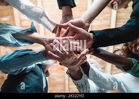 Group of businesspeople joining hands together standing in circle, closeup view from bottom - Creative business teamwork building concept - soft skill Stock Photo
