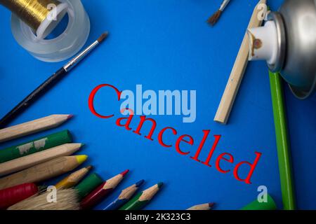 Overhead shot of school supplies with Cancelled text. Brushes, pencils, artistic tools. Art And Craft Work Tools. Stock Photo