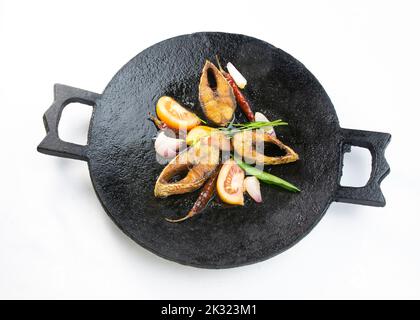 Ilish bhaji for Panta ilish, Bengali new year festive dish. Fried Hilsha slices with chilli, tomato and onion. Ilsha fry on black pan. Hilsa fry is po Stock Photo