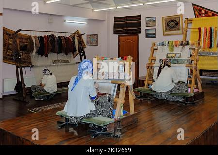 The showroom of the carpet factory where the tourists can see how the unidentified women work at looms in Denizli, Turkey Stock Photo