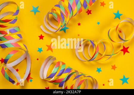 yellow background with colorful serpentine and star shaped confetti, concept for circus or birthday party, anniversary, congratulations.  Stock Photo