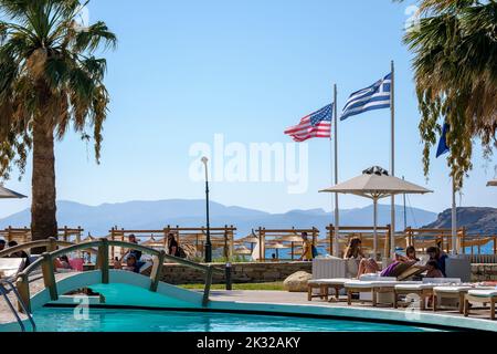 Ios, Greece - September 13, 2022 : Young female  tourists enjoying an outdoor swimming pool in front of the famous Mylopotas beach in Ios Greece Stock Photo