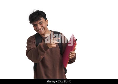 Young peruvian student pointing at someone and smiling, isolated. Stock Photo