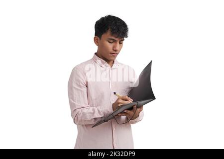 Young peruvian man writing on a folder with a pen, isolated. Stock Photo