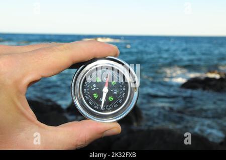 A closeup of male hand holding round metal compass Stock Photo
