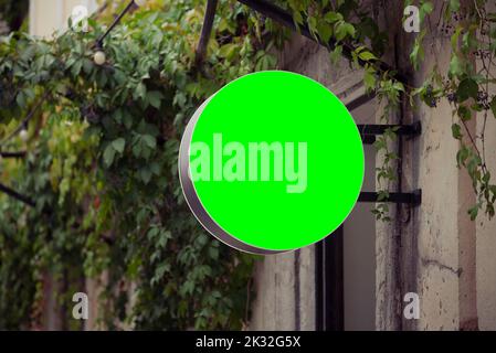 Round banner on the old wall with green vines on background. Metal cafe or shop badge Stock Photo
