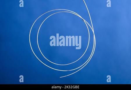 coiled metal wire, blue background Stock Photo