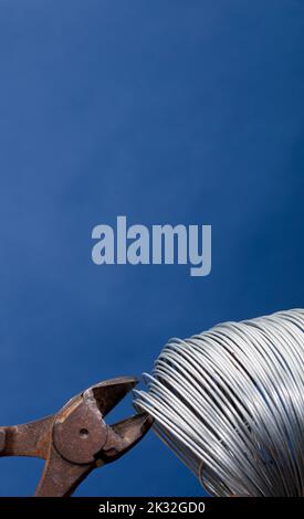 coiled metal wire cutting pliers, blue background Stock Photo