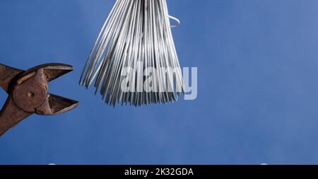 coiled metal wire cutting pliers, blue background Stock Photo