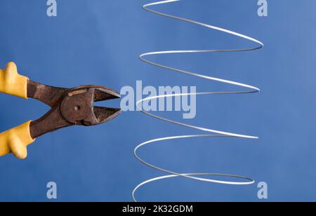 coiled metal wire cutting pliers, blue background Stock Photo