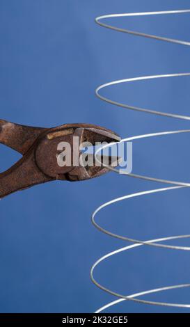coiled metal wire cutting pliers, blue background Stock Photo