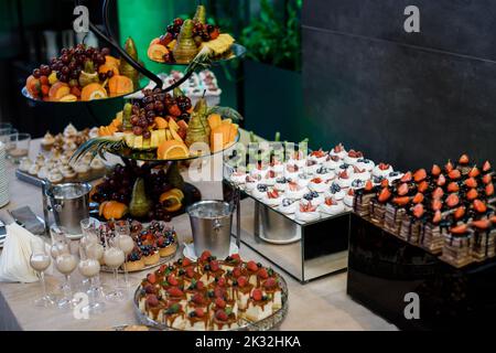 Wedding. Candy bar. On the buffet table there are glasses with drinks, fruits and different sweets. Stock Photo
