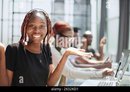 Smiling beautiful African American woman working in call center with diverse team Stock Photo