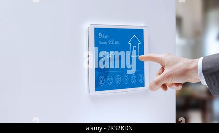 Man checking a smart home touch screen control panel, home automation concept Stock Photo