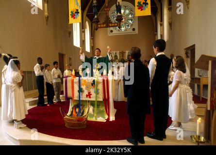 Priest at Altar performing the Eucharist at First Communion St Joseph's Church Roehampton London England Stock Photo