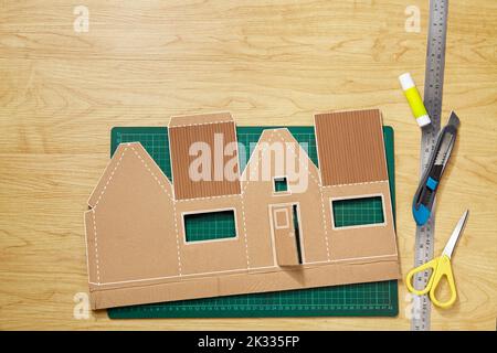 A craft pattern from cardboard that has been cut, ready to be shaped and glued into a miniature house Stock Photo