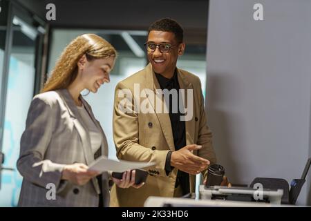 Two business people are talking while scanning documents on a scanner Stock Photo