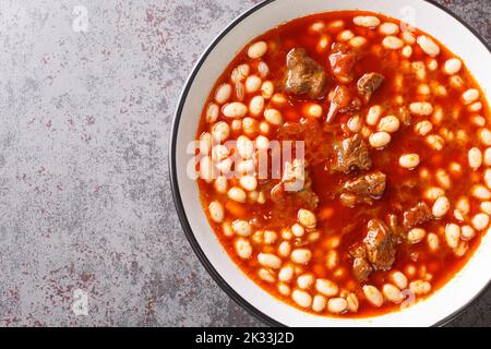Spicy Turkish food Kuru Fasulye from beans with lamb in tomato sauce close-up in a bowl on the table. horizontal top view from above Stock Photo