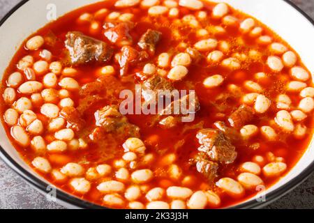 Spicy Turkish food Kuru Fasulye from beans with lamb in tomato sauce close-up in a bowl on the table. horizontal Stock Photo