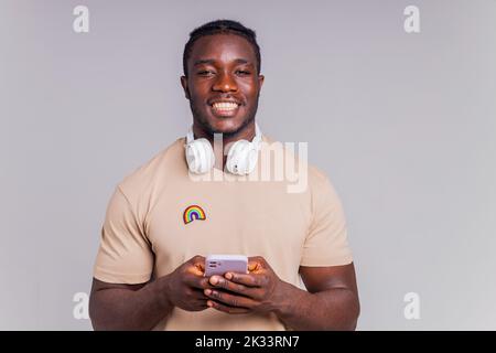 latino man in casual gray t-shirt wearing wireless headphones and using smartphone Stock Photo