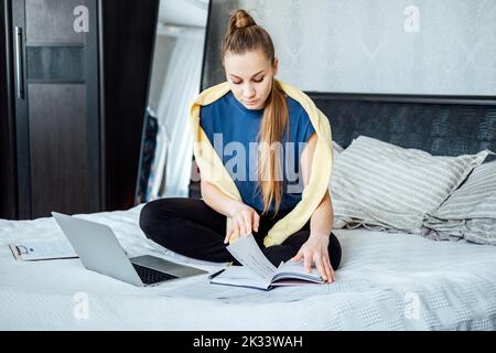 Job search concept, find your career. Young woman looking a job at online website by laptop computer sitting on bed at home. Stock Photo
