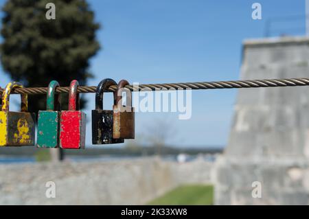 Old and rusty love padlocks locked on the steel cable, symbol of eternal love, in Pula, Croatia Stock Photo