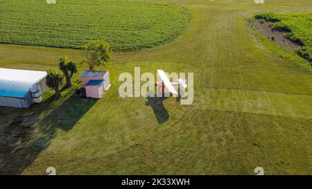 Plane parked in front of a hangar on a grass runway Stock Photo