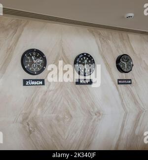 In the hotel, the clock on the wall shows the time in various cities of the world: Zurich, Kiev, Warsaw. Stock Photo
