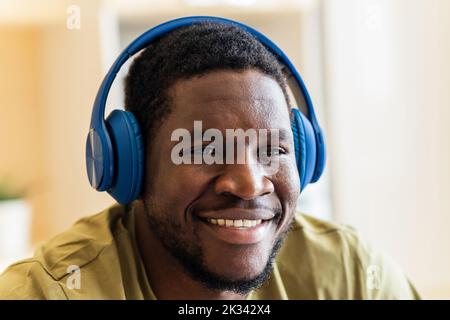 hispanic man listening music in wireless headphones at home Stock Photo
