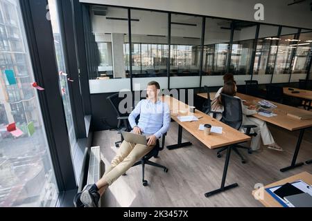 Thoughtful corporate employee and his busy coworkers in workplace Stock Photo