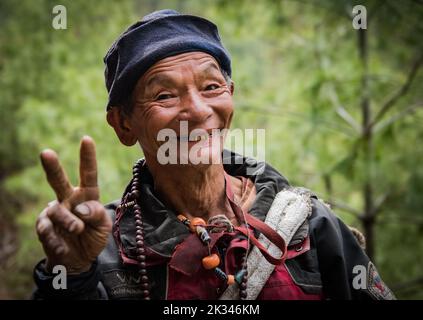 Portrait of an elderly Nepalese man showing a victory sign with his right hand. Stock Photo