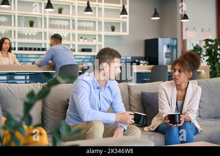 Woman and her colleague sitting on sofa at coffee break Stock Photo