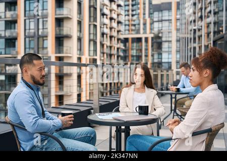 Young corporate employee communicating with his coworkers during coffee break Stock Photo