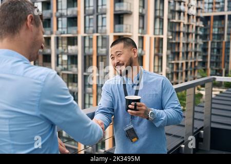 Company employees shaking hands during coffee break Stock Photo