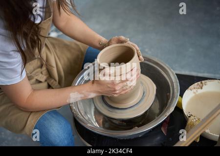 Craftswoman forms a clay pot on a potter wheel Stock Photo