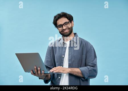 Happy arab business man student holding laptop isolated on blue. Stock Photo