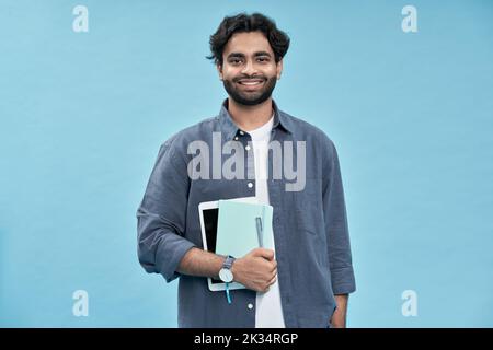 Smiling arab young man student standing isolated on blue background. Stock Photo