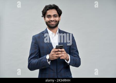 Smiling arab indian business man using mobile phone isolated on beige. Stock Photo