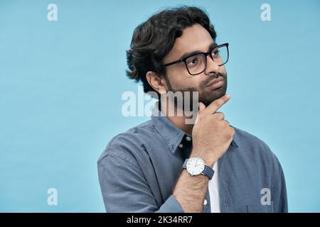 Thoughtful young arab man looking aside isolated on blue background. Stock Photo