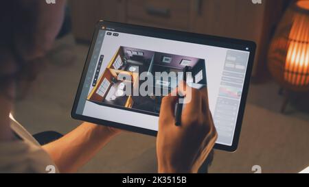 Male 3D designer using digital tablet computer and pencil and creating interior of house in professional design application while working on project remotely Stock Photo