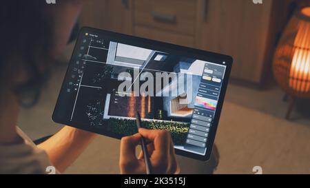 Male 3D designer having remote freelance project and working on smart house exterior in 3D modeling application using digital tablet computer and pencil Stock Photo