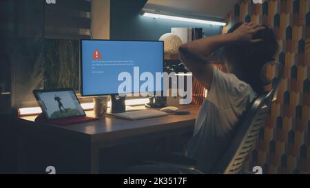 Upset male 3D designer having computer error while working on development of video game hero and 3D animation remotely at home at night Stock Photo