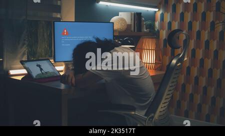 Upset male 3D designer having computer error while working on development of video game hero and 3D animation remotely at home at night Stock Photo