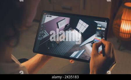Male 3D designer using digital tablet computer and pencil and creating interior of house in professional design application while working on project remotely Stock Photo