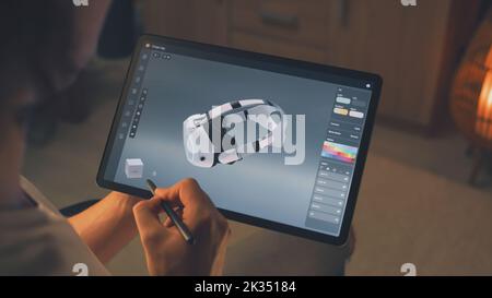 Young male 3D designer drawing and creating 3D prototype of VR headset in professional design application on tablet using digital pencil Stock Photo