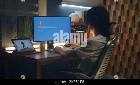 Upset male 3D designer having computer error while working on development of video game hero and 3D animation remotely at home at night Stock Photo