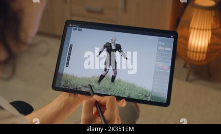 Male 3D designer creating 3D animation of video game character in design application on modern digital tablet computer using stylus Stock Photo