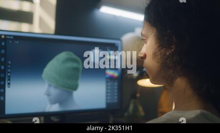 Guy sitting at the table and designing clothes in 3D modeling professional program on personal computer while working remotely from home Stock Photo