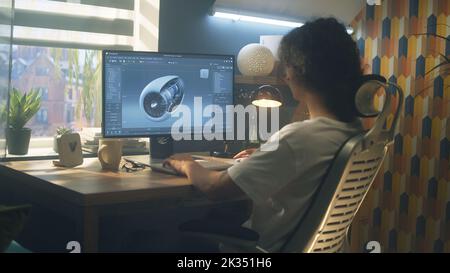 Male young engineer using pc with professional program and creating 3D prototype of airplane turbine while working remotely at home office Stock Photo